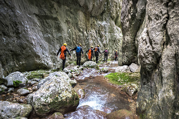 Members of canyoning team moving through the corridor of rocks and small water stream in the canyon.