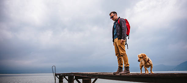istock Man and his dog standing on wooden dock 603849106