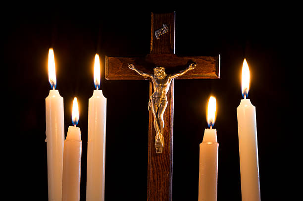istock Crucifix among lighting candles on black background 603850390