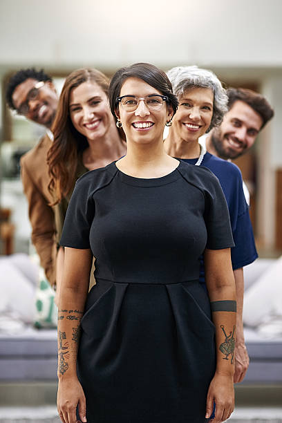 The dream team at your service Portrait of a group of businesspeople standing in a line in an office workplace diversity vertical stock pictures, royalty-free photos & images