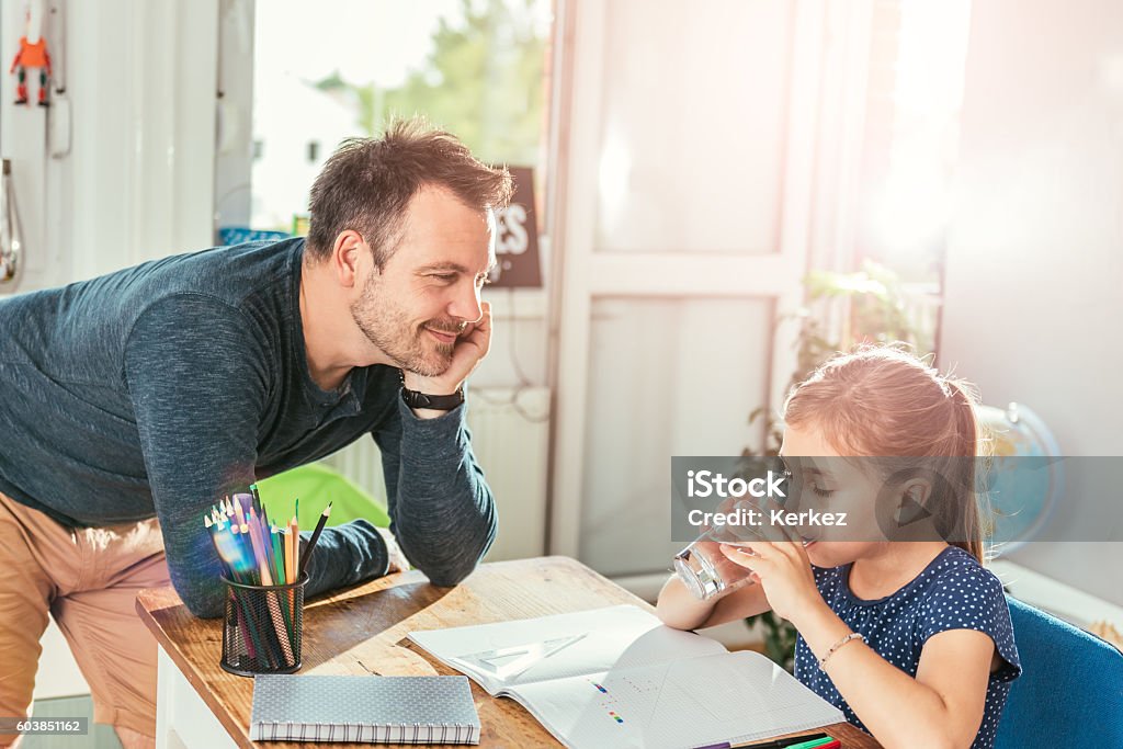 Girl drinking water Girl drinking water while doing homework and father standing next to her Drinking Stock Photo