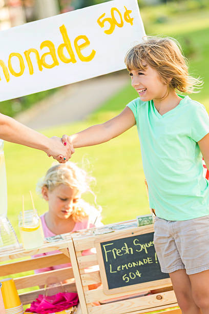 istock Young entrepreneur shakes hand with customer at lemonade stand 603851380