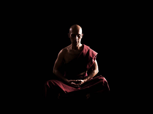 buddhist monk in meditation pose over black background