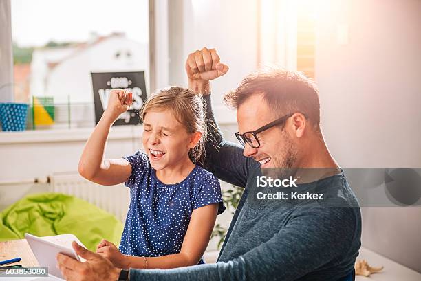 Father And Daughter Cheering During Playing Game On Tablet Stock Photo - Download Image Now