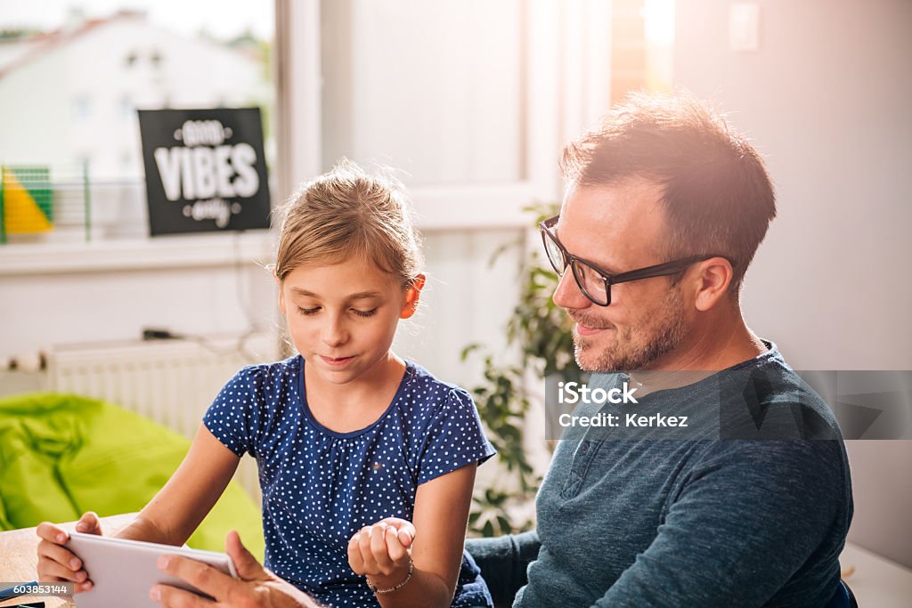Father and daughter using tablet Father and daughter using tablet at home to finish homework Father Stock Photo