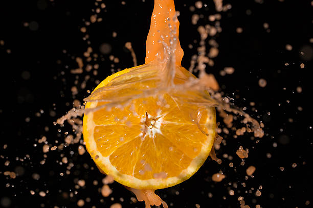 istock Orange and orange juice splash on a black background 603854020