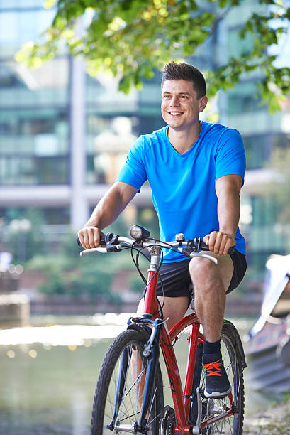 istock Young Man Cycling Next To River In Urban Setting 603856344