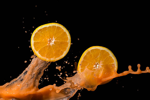 istock Oranges and orange juice splash on a black background 603856724