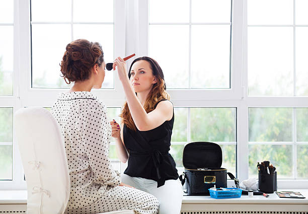 Make-up artist doing make up for young beautiful bride