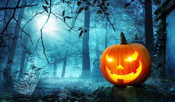 Jack o lantern in blue moonlight Glowing Jack o lantern in a creepy old overgrown cemetery with cool blue moonlight halloween pumpkin scary stock pictures, royalty-free photos & images