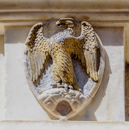 An eagle in a crest is carved on a stone wall in a renaissance building in Florence, Italy