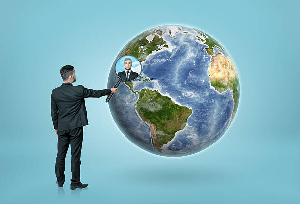 istock Businessman looking through magnifying glass on Earth 603864830