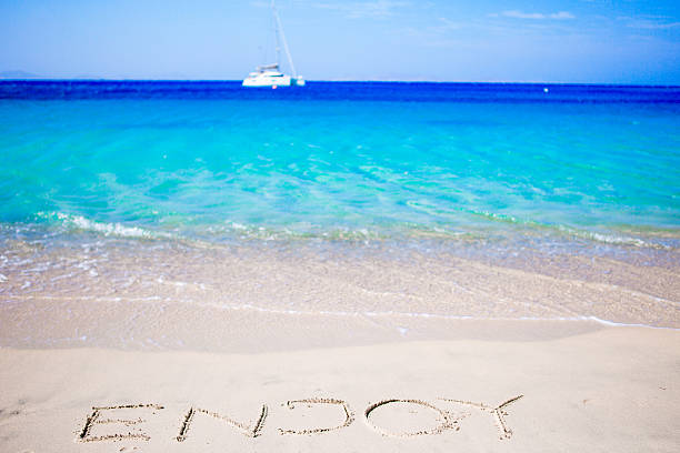 istock Word Enjoy handwritten on sandy beach with soft ocean wave 603871520