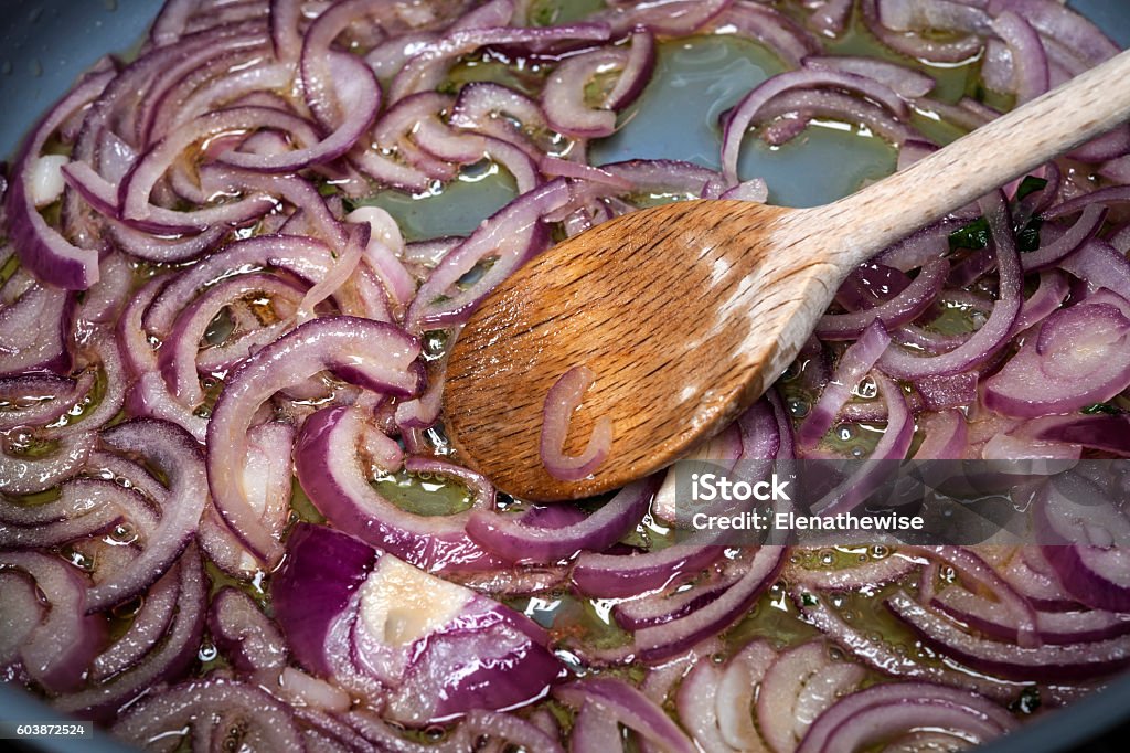 Sauteed onions Stirring sauteing red onions with wooden spoon in cooking pan, closeup Onion Stock Photo