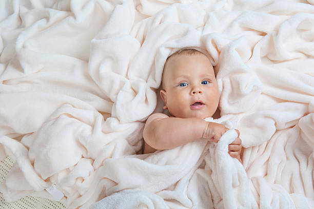 istock Caucasian baby boy covered with  towel joyfully smiles at camera 603872794