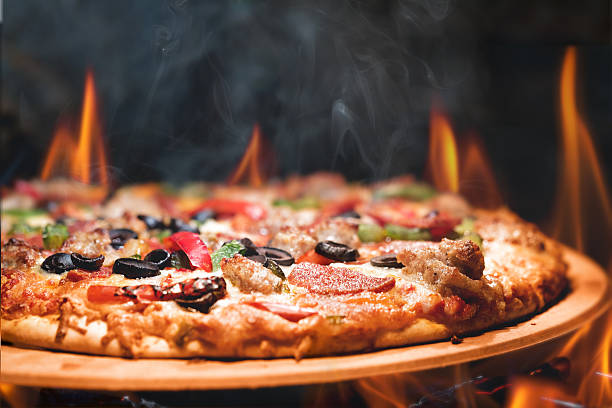 Wood Fired Pizza With Flames Supreme meat and vegetable pizza on stone in wood-fired oven with open flames italian food photos stock pictures, royalty-free photos & images