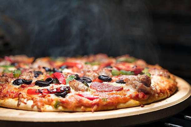 Hot Steaming Pizza in Oven Hot supreme thin crust pizza cooking in oven with steam and smoke steam photos stock pictures, royalty-free photos & images