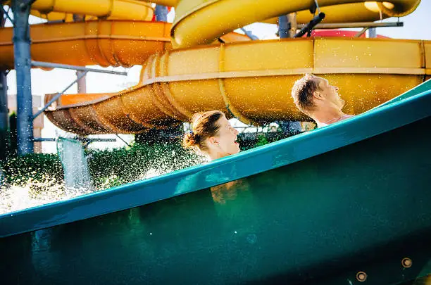 Photo of Happy Couple Enjoying Water Slide in swimming pool