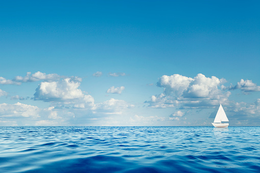 Blue sea with white sailboat on the horizon.