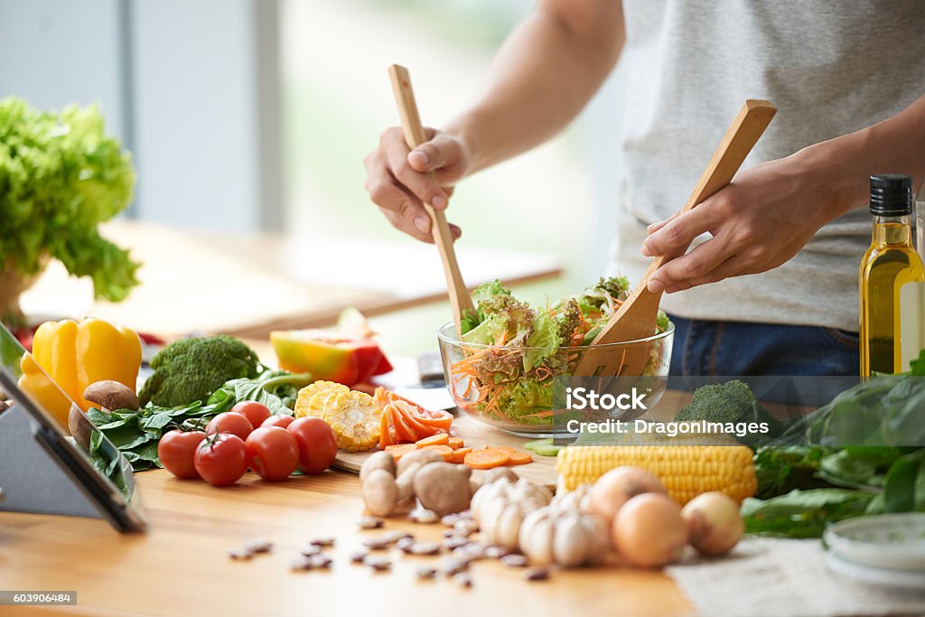 Vegetable salad Vegetarian man mixing vegetable salad in bowl Healthy Eating Stock Photo