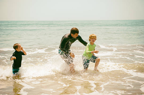 Father and children play in the ocean together