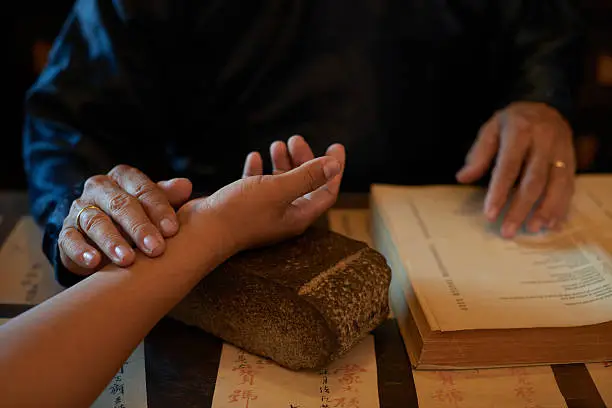 Asian traditional practitioner checking pulse of patient before treatment