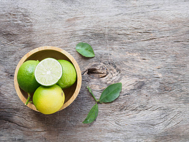 istock Top view of lime in bowl on rustic wooden background 603907548