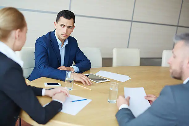 Serious manager looking at one of co-workers during discussion