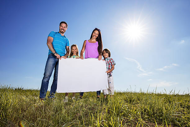 below view of happy family holding blank placard in nature. - child women outdoors mother imagens e fotografias de stock