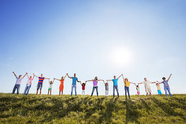 istock Group of cheerful people standing in nature and holding hands. 603912802