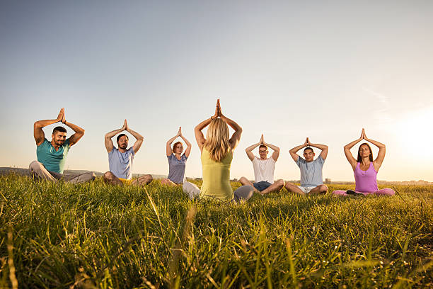 istock Group of people practicing yoga on the grass at sunset. 603913328