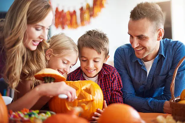 Photo of Parents helping children in carving pumpkins