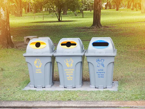 recycle bins with symbol kind of garbage in the park at sunset