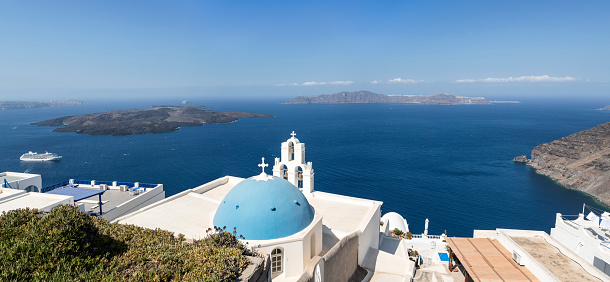 Morning view in Santorini of the Fira church sitting on top of the volcanic caldera. Santorini in Greece is one of the most famous travel destination in the World with numerous cruise ships anchoring in the bay below. The architecture is also famous for the duotone colors of the white painted buildings and light blue details.