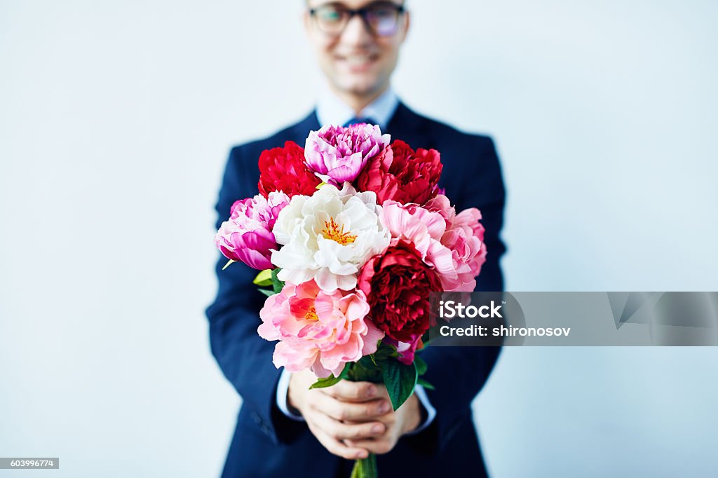 Take these flowers Elegant man giving a beautiful bouquet of red and white flowers Flower Stock Photo