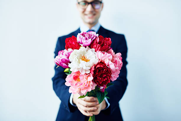 Take these flowers Elegant man giving a beautiful bouquet of red and white flowers man flower stock pictures, royalty-free photos & images