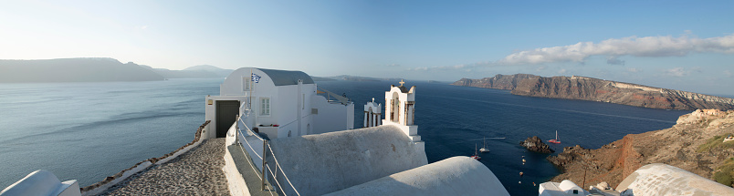 Early morning view of a small Greek chapel at the village of OIA facing the volcanic caldera in Santorini, a place famous worldwide for the churches and chapels painted in white. Santorini in Greece is one of the most famous travel destination with numerous cruise ships anchoring in the bay below.