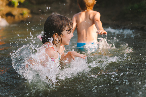 Children playing in a river in hot summer day
