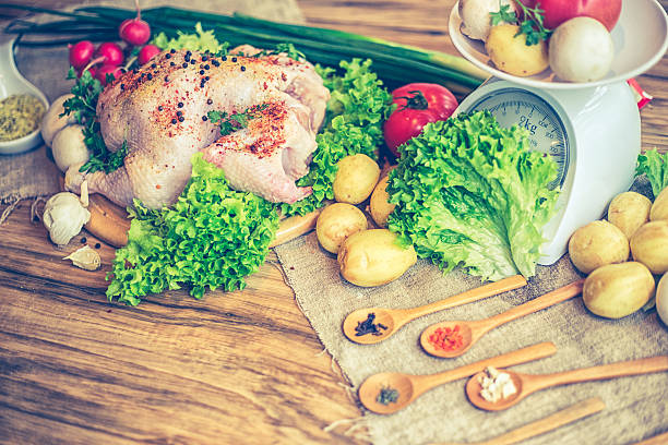 Whole raw chicken with vegetables and kitchen scales