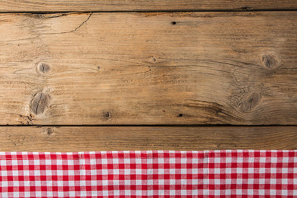 istock Checkered tablecloth red on the wooden background/ texture 604010212