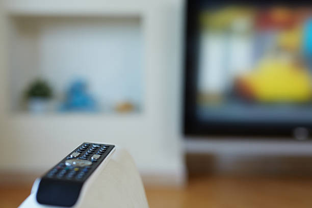 TV remote Focus on remote control for TV lying on sofa armrest couch arm rest stock pictures, royalty-free photos & images