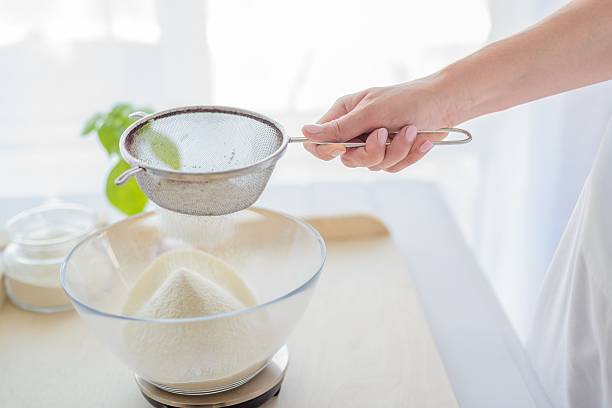 istock Woman sifting flour through sieve. 604014352
