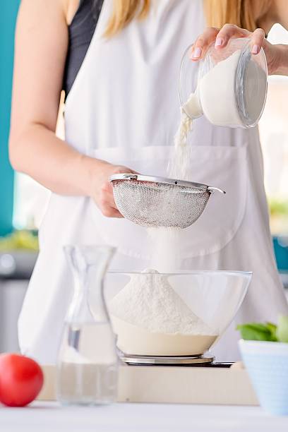 istock Woman sifting flour through sieve. 604014460