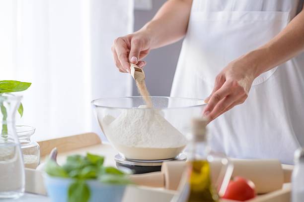 kobieta dodająca sproszkowane drożdże do mąki - on eggs standing spoon zdjęcia i obrazy z banku zdjęć