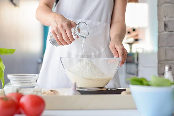 istock Woman adding water to flour in a bowl. 604015100