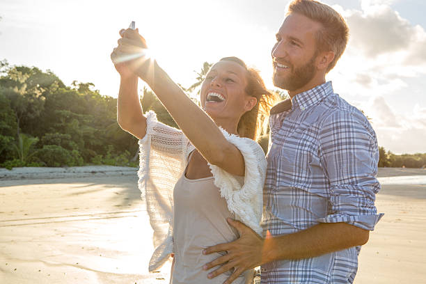 istock Happy couple on beach take selfie portrait using mobile phone 604016288