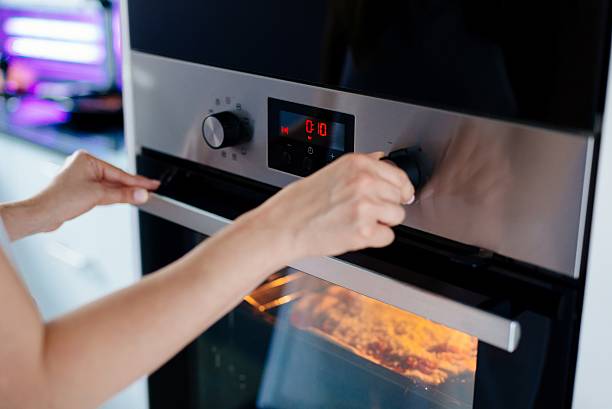istock Woman regulates the time of the baking 604017932