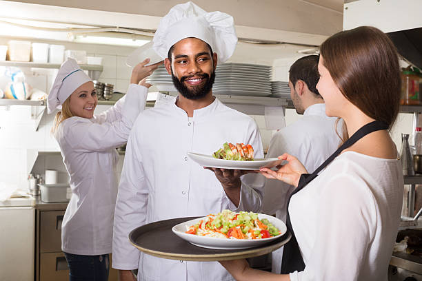 istock Waitress and crew of professional cooks posing at restaurant 604018262