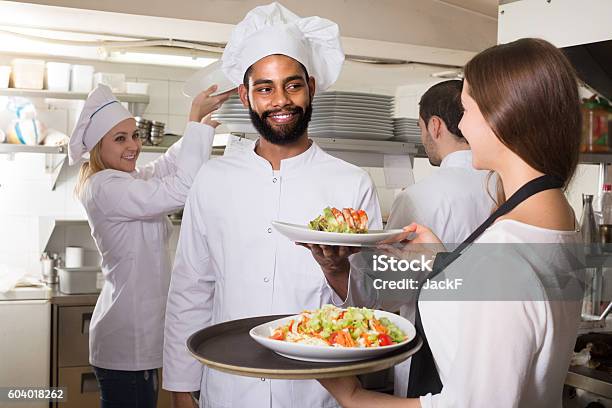 Waitress And Crew Of Professional Cooks Posing At Restaurant Stock Photo - Download Image Now