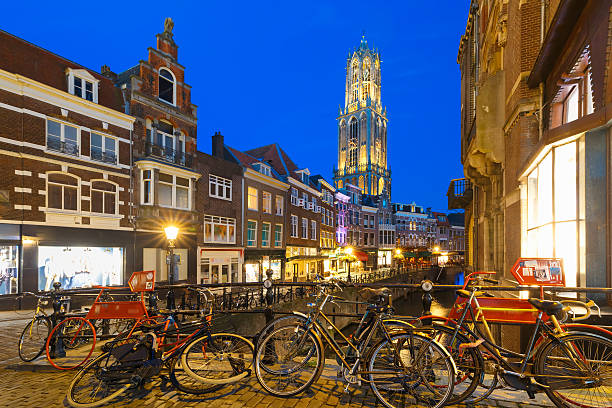 Dom Tower, bridge, bikes and canal Oudegracht in the night colorful illuminations in the blue hour, Utrecht, Netherlands
